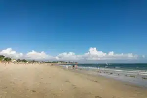 Plage de sable fin à Carnac avec vacanciers et voiliers
