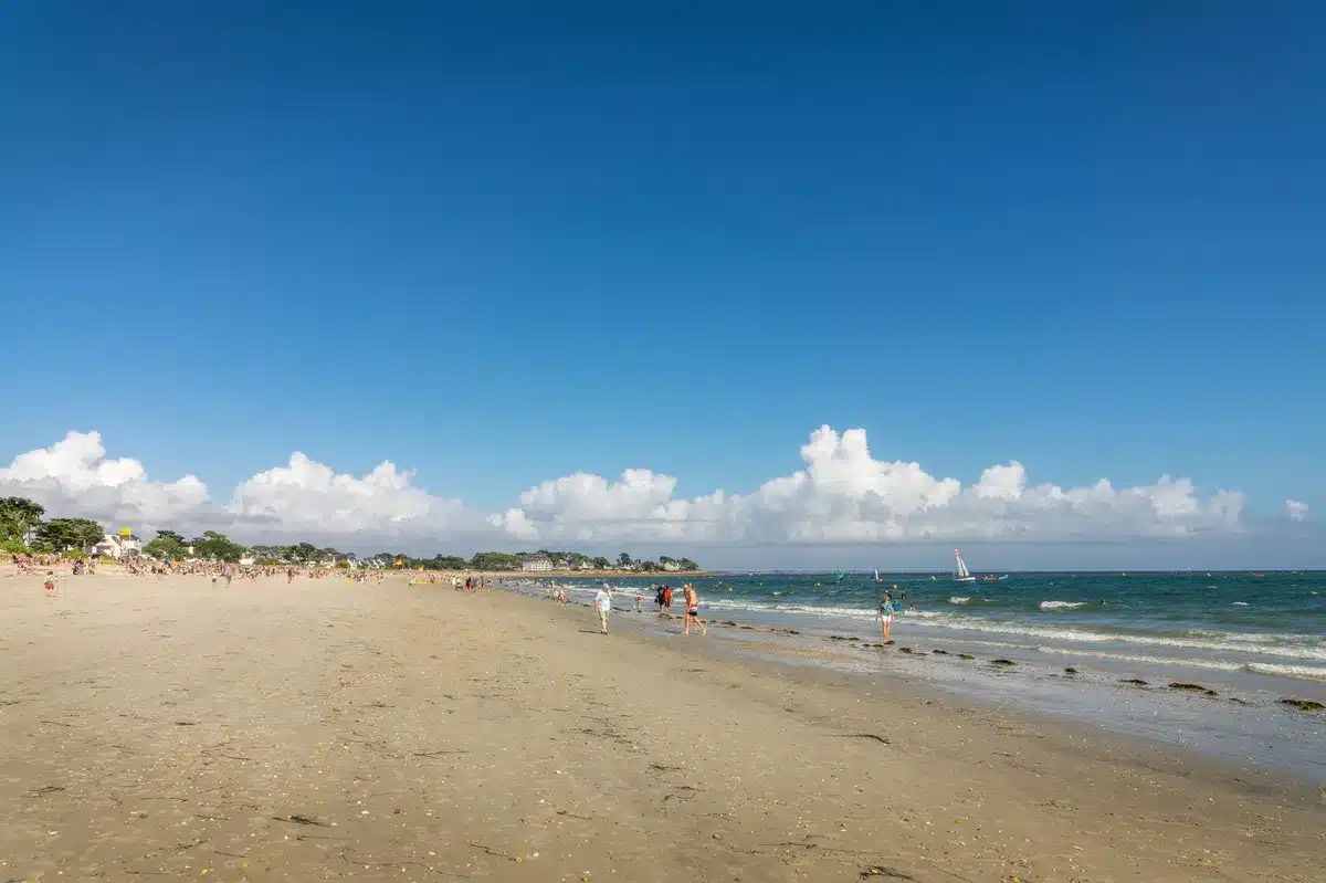 Plage de sable fin à Carnac avec vacanciers et voiliers
